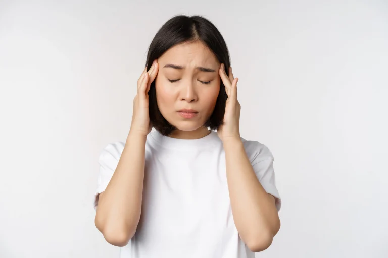 Portrait of asian girl feeling headache migraine or being ill standing in white tshirt over white background