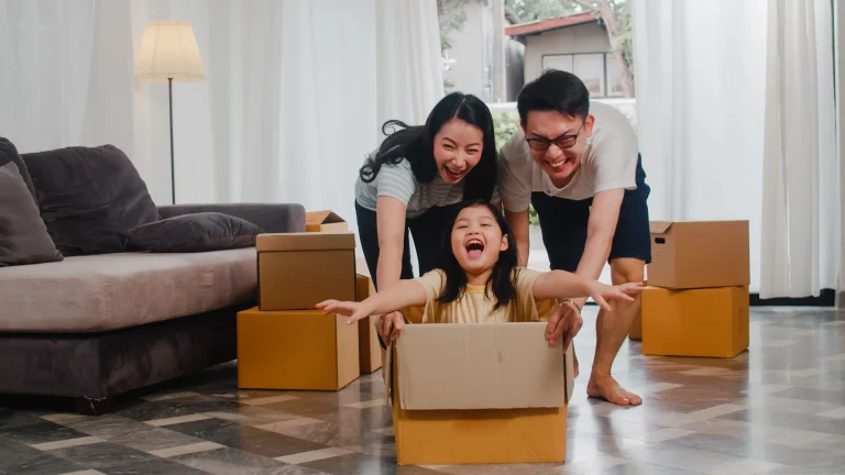 Happy Asian young family having fun laughing moving into new home